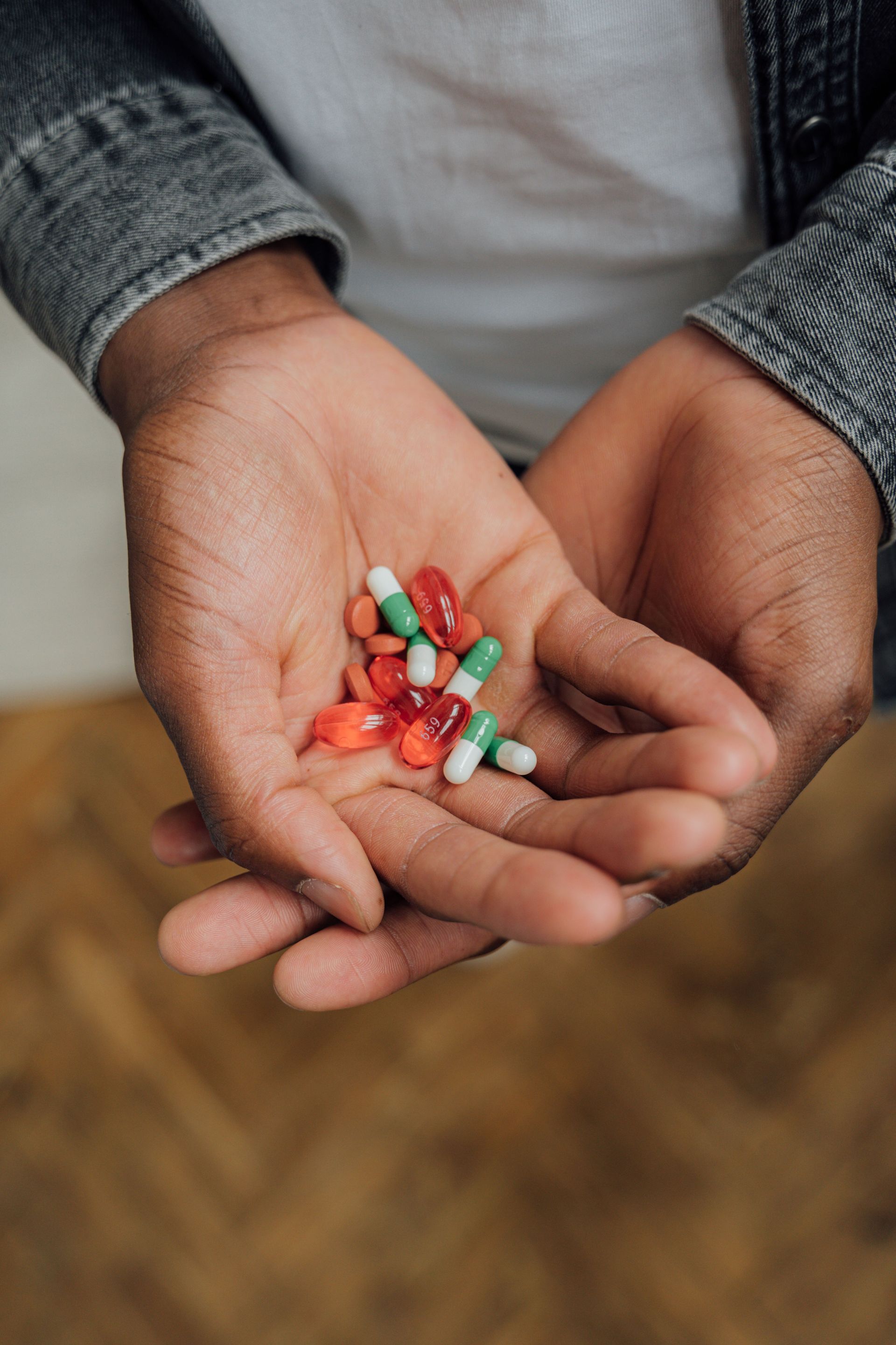 A close-up image of hands holding various colorful capsules and tablets, symbolizing medication or supplements.